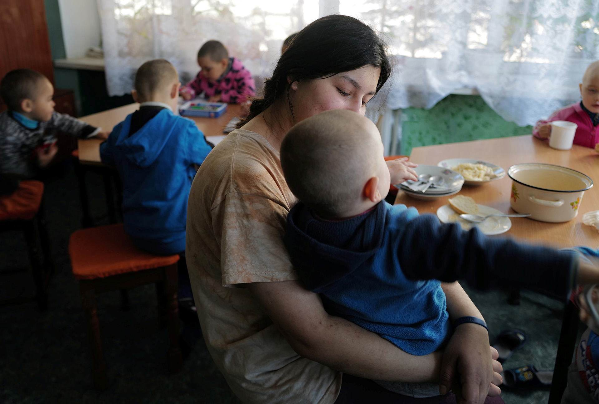 A volunteer holds a boy as he has breakfast in a state shelter in Lviv, Ukraine for children in foster care on 25 March.