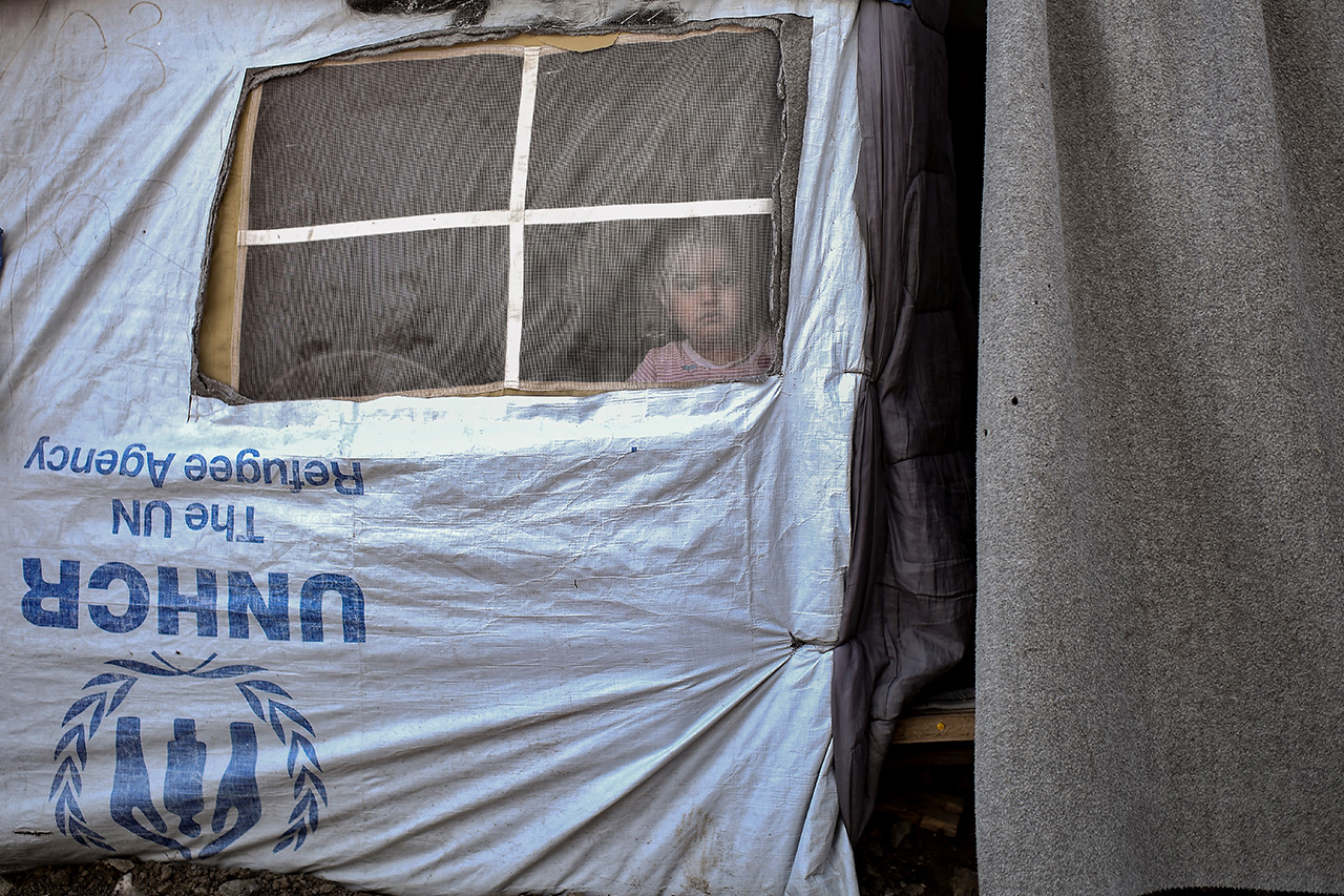 A child looks out of a tent in a camp next to the Moria detention centre on the island of Lesvos.