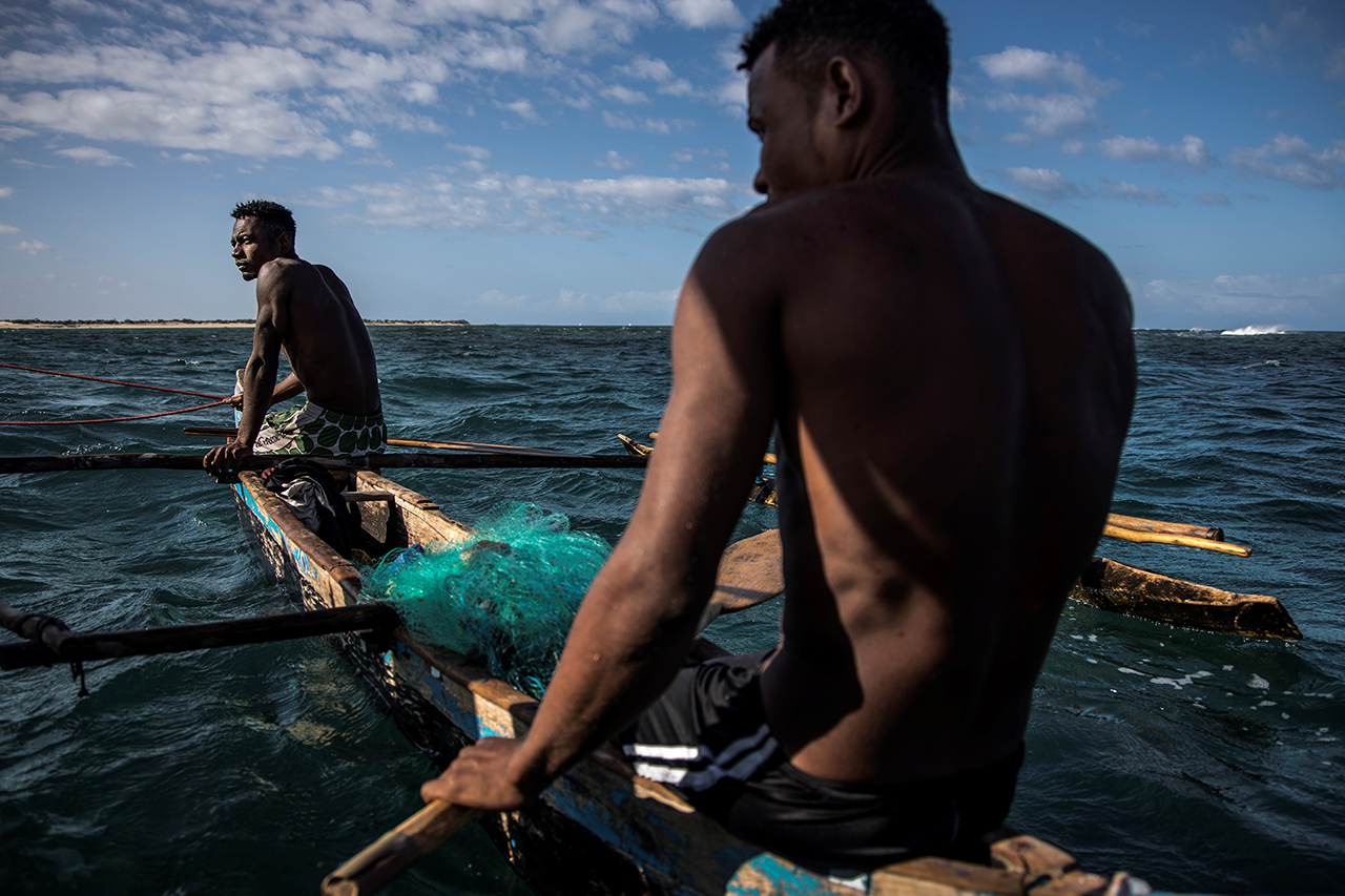 Two fishermen at sea on a small boat
