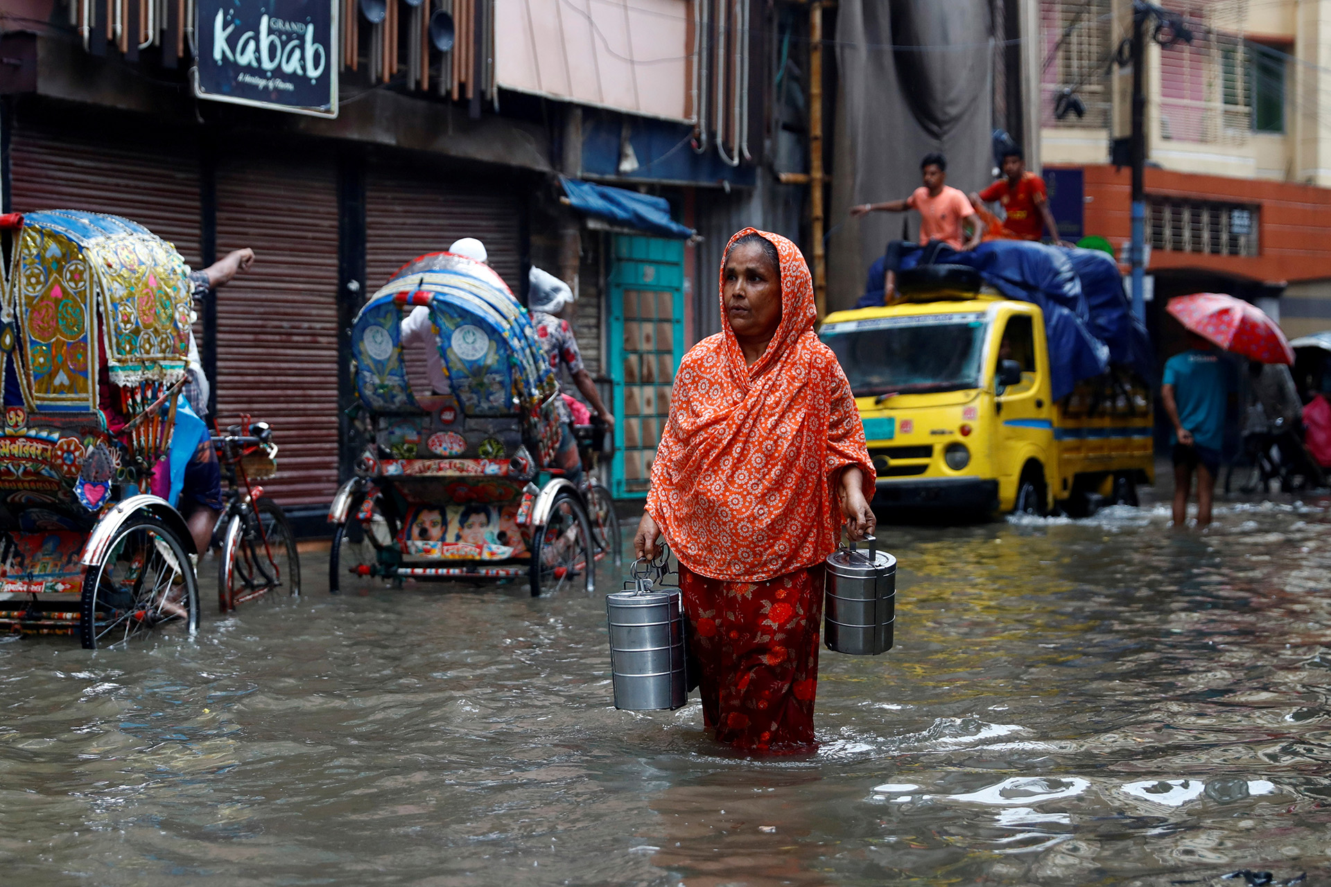Commuters move through a water-logged street after heavy rain in Dhaka, Bangladesh, 21 July 2020.