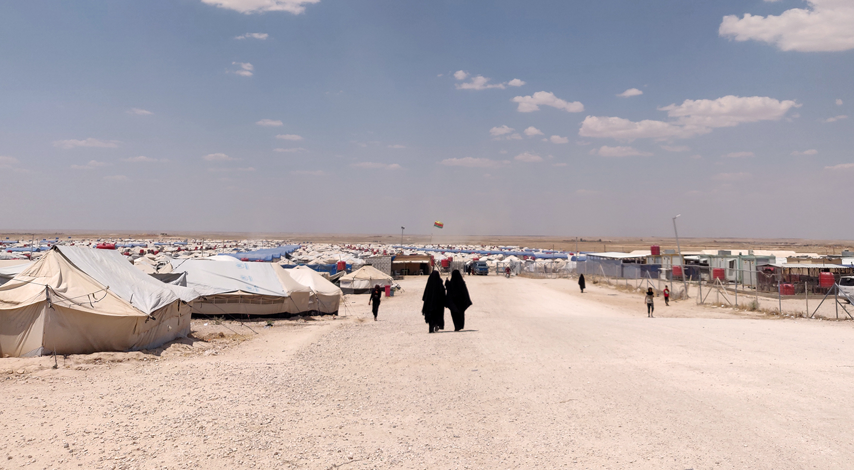 Photo of al-Hol camp in Syria showing a dry landscape and temporary shelters.