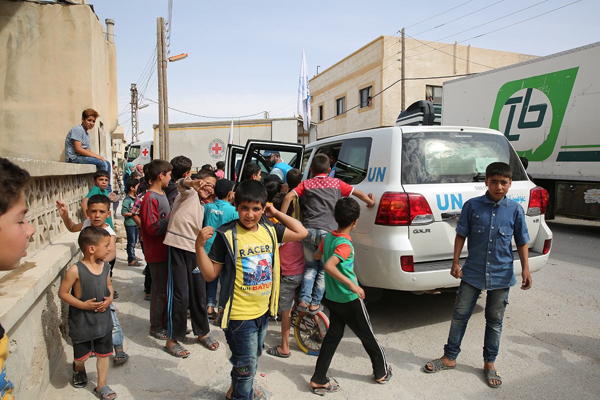 Children gather on the streets of the remote farming town Jayrud to greet a convoy of inter-agency trucks delivering long awaited supplies