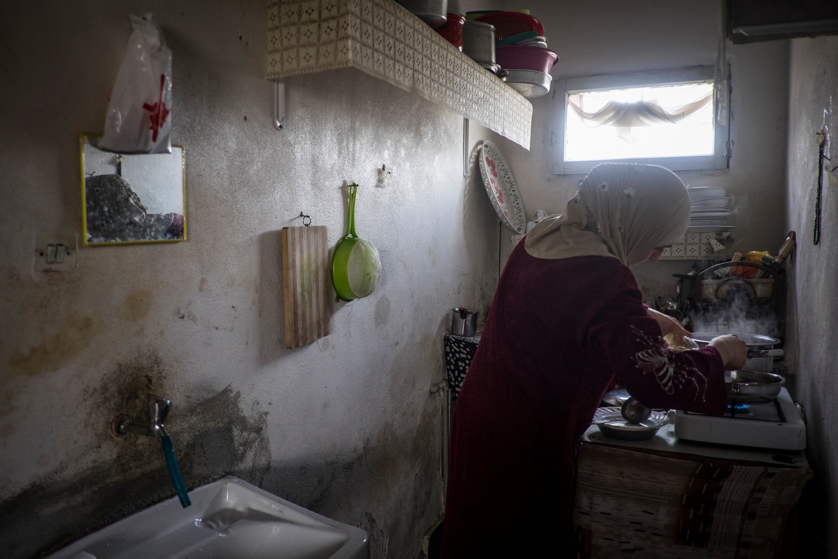 A woman cooks in a basement flat