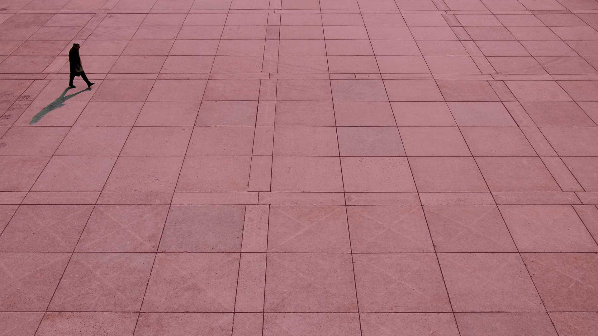 Man walking across open concrete space