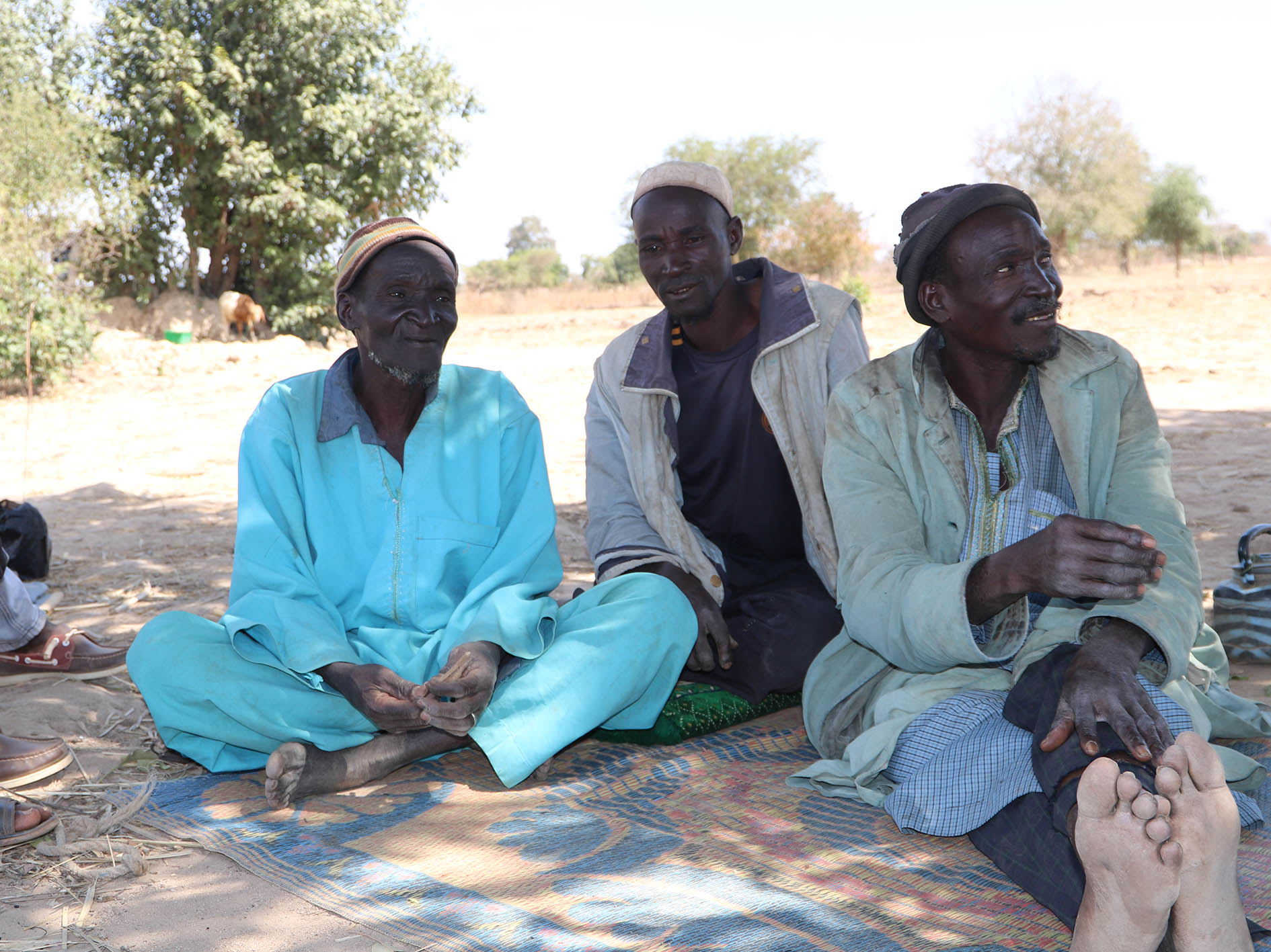 Yanga Amadou sits with his family under a tree, where they now live, on the edge of Fada town in eastern Burkina Faso.