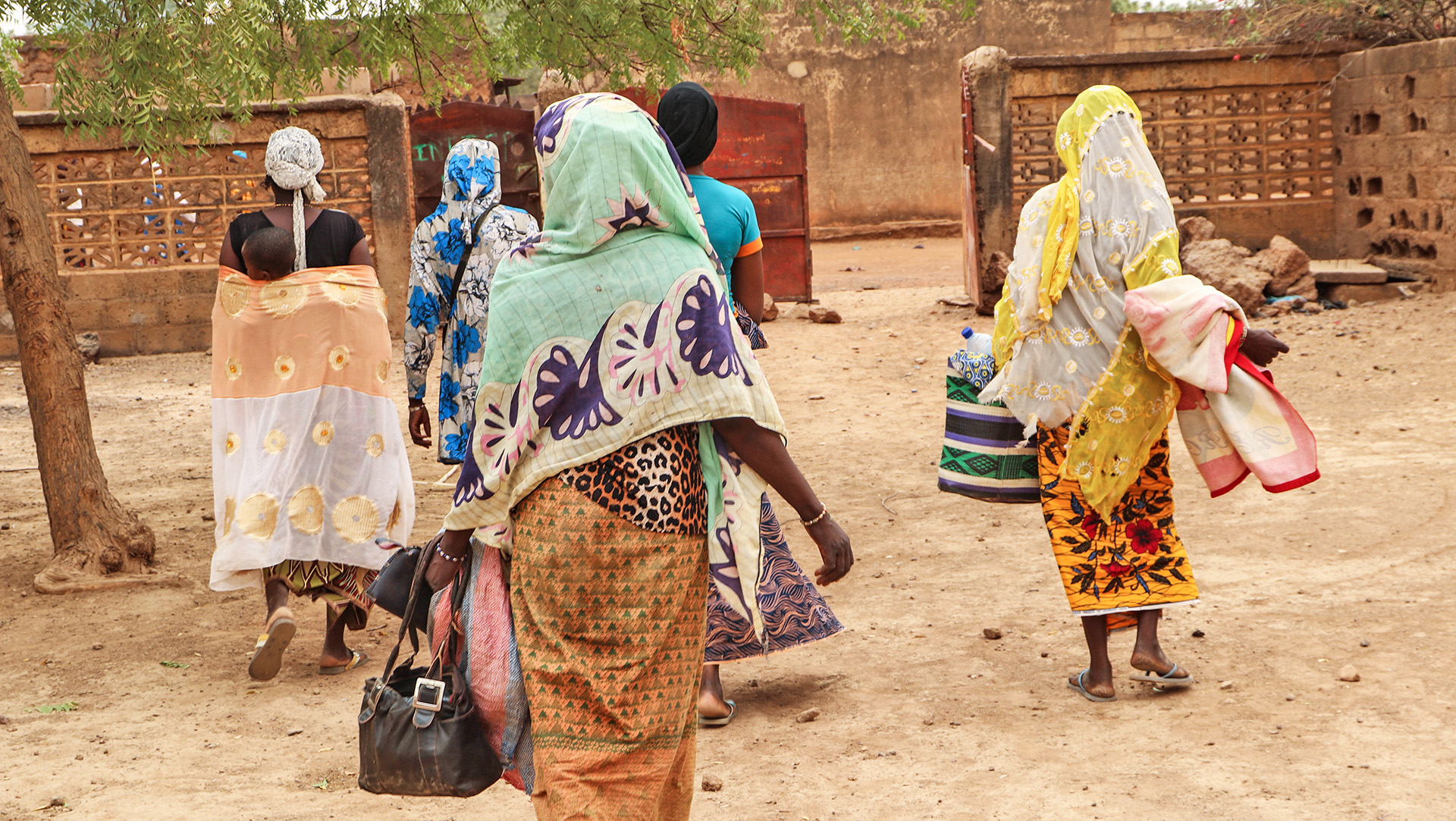 Women walking out of a compound in the northern town of Kaya after speaking to The New Humanitarian about how they were solicited for sex while trying to get food aid.