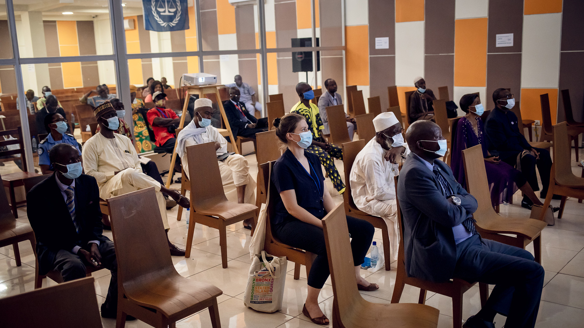 The photo shows a scattered crowd of people sitting in chairs watching the screening, which is out of view.