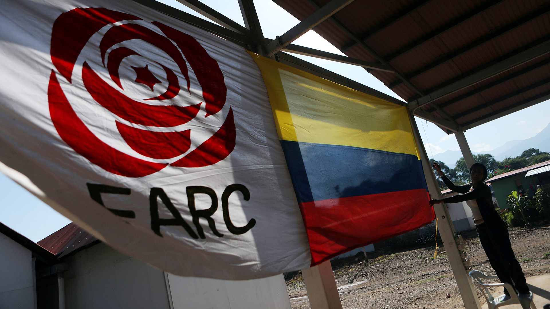 A woman hangs a Colombian flag next to a FARC political party flag