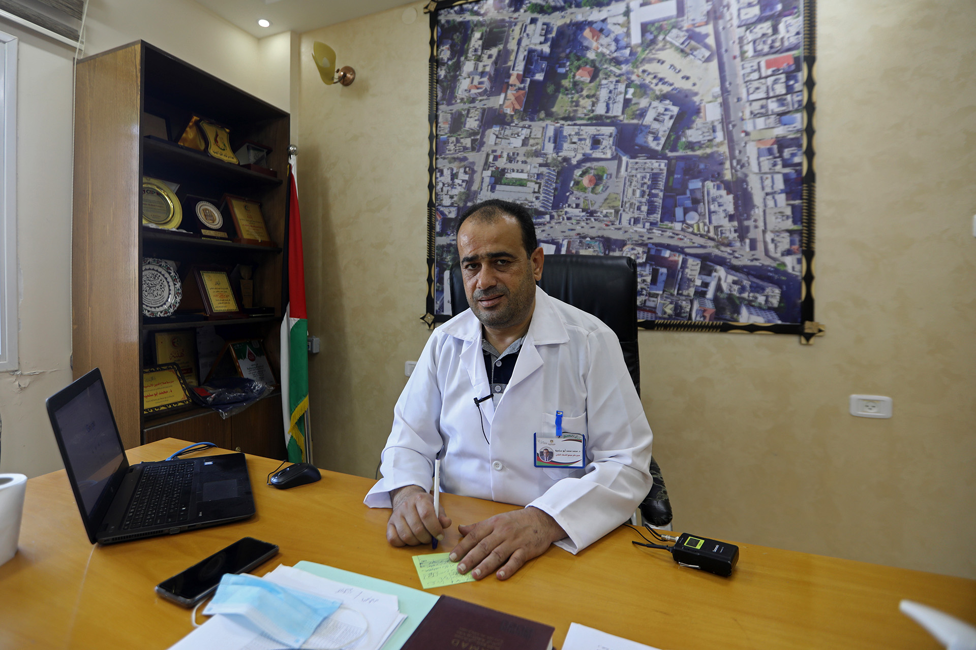 A doctor sits behind a desk in his office.