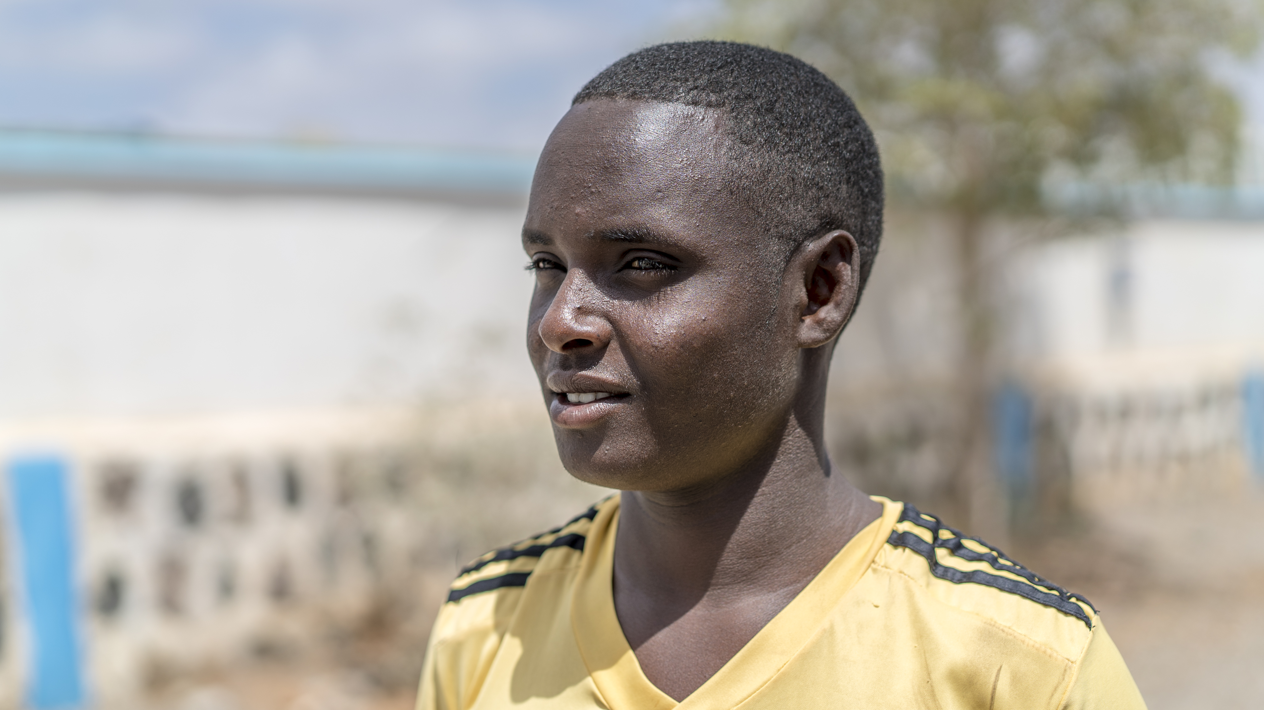 Portrait of an Ethiopian young man looking off camera wearing a yellow, athletic v-neck shirt