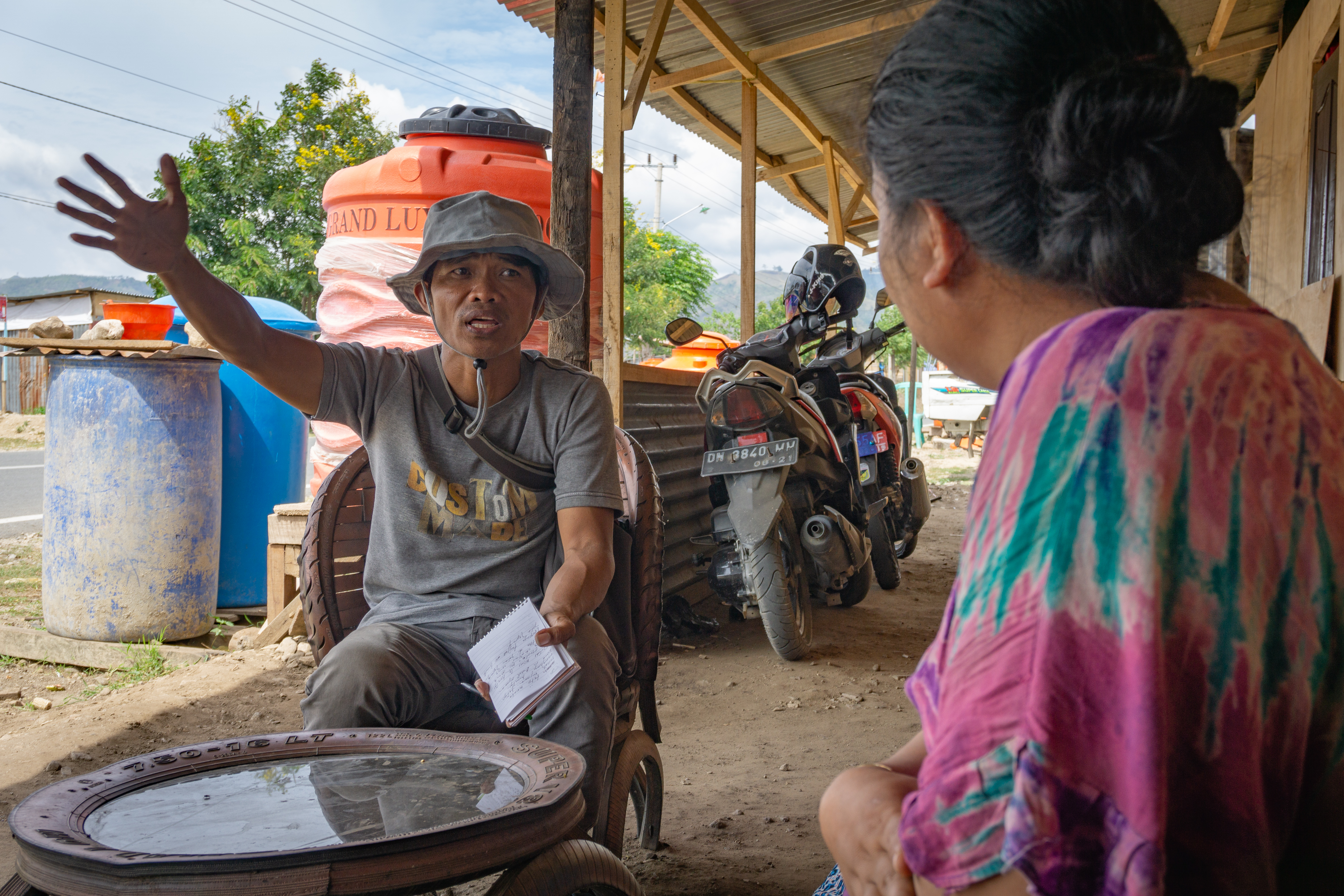 Local journalist Yardin Hasan interviews a family who built their own wooden shelter on the outskirts of Palu, Indonesia