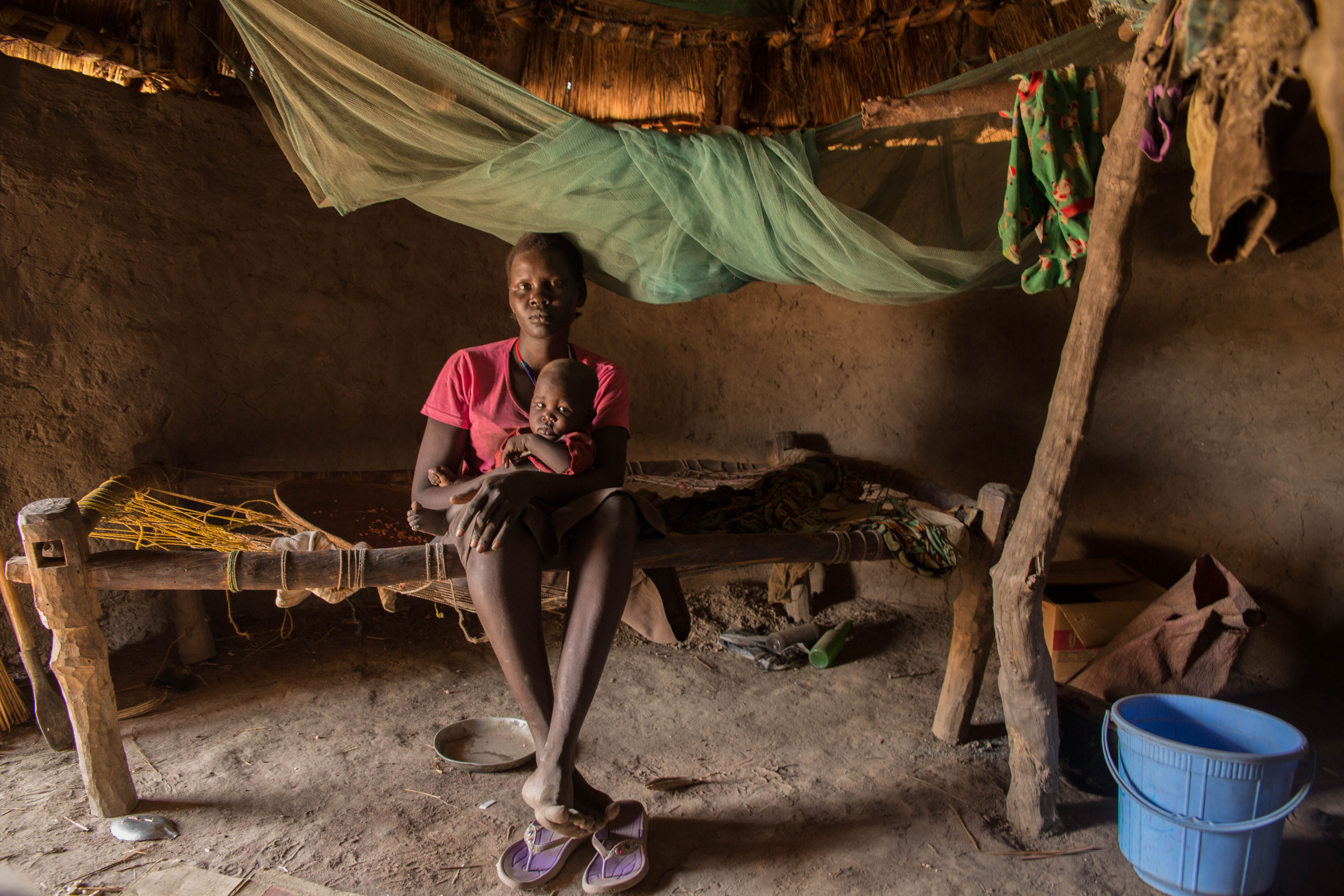 Adut Adak sits in her small mud hut