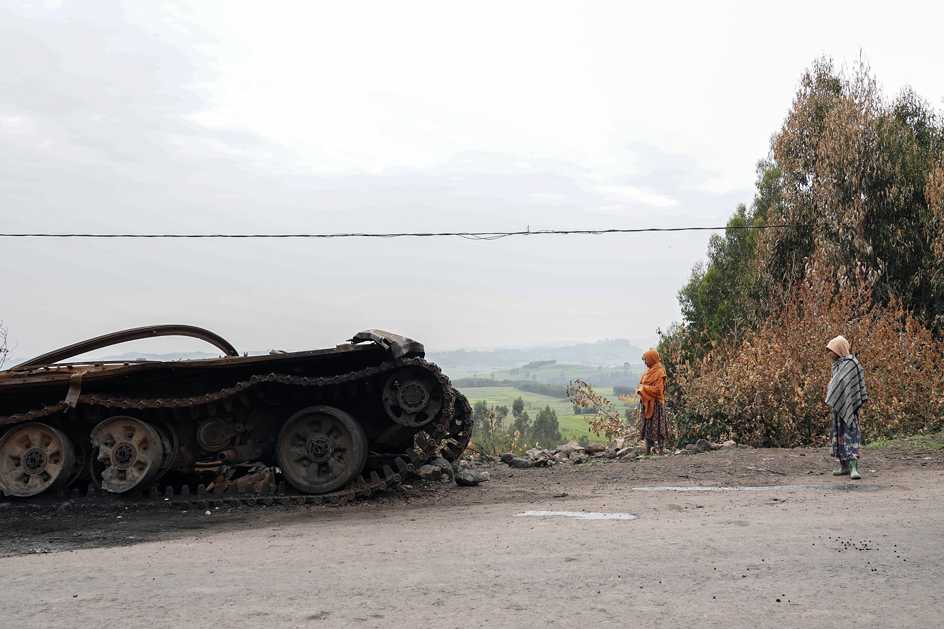 Residents walk past an abandoned tank on a main road in Amhara region. Fighting has intensified in recent days after the government launched a fresh anti-rebel offensive.