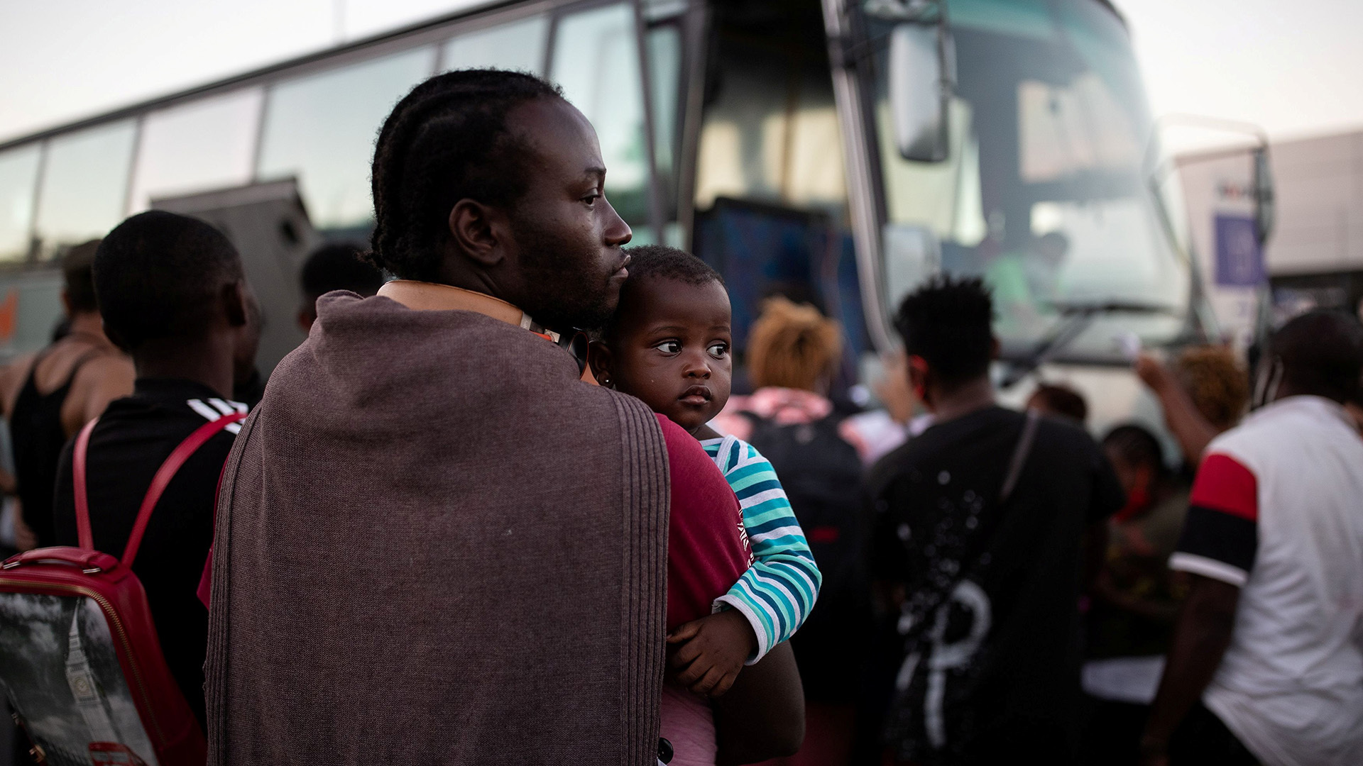 A man holds a child as refugees and migrants wait to board a bus following last month’s fire at the Moria camp on the island of Lesvos, Greece.