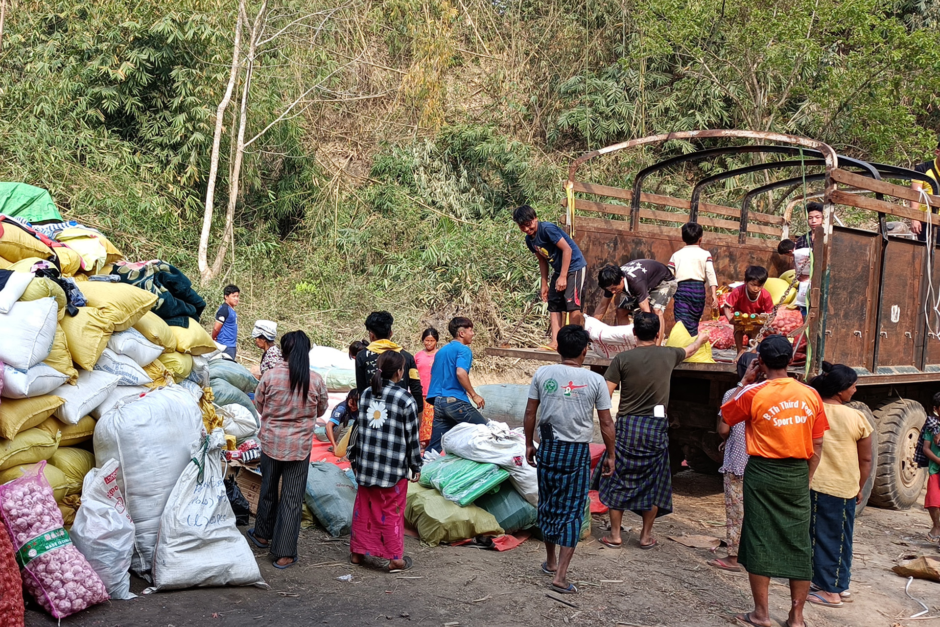Several people stand around a truck unloading aid items.