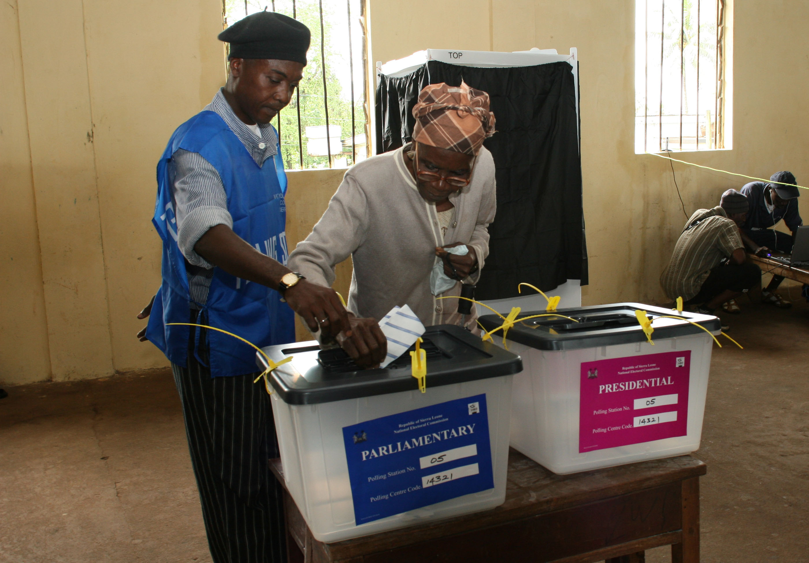 A woman is helped by a member of the polling staff to cast her vote at a polling station in Freetown, Sierra Leone, 11 August 2007. Sierra Leone's presidential and parliamentary elections were the first to be organised internally since 17,500 UN peacekeep
