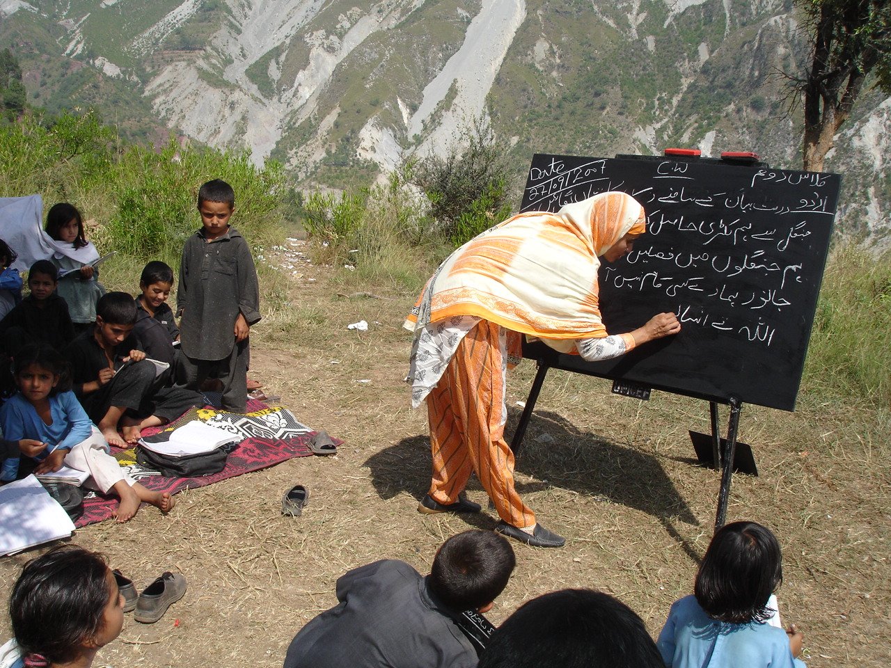 Nasrat Kazmi, a teacher at the Sherwan government primary school outside Muzaffarabad, teaches her class outside - two years after a devastating earthquake destroyed their school.
At least 17,000 students and 900 teachers died in the 8 October 2005 - tha