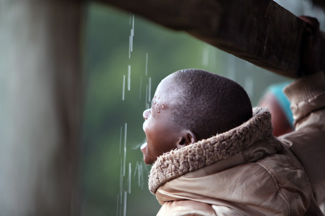 A young boy drinks rain water at the displaced camp in Eldoret, Kenya, April 2008. The heavy downpour brings a risk of waterborne diseases that can hit the camp.