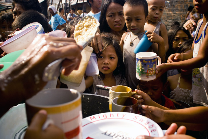 Residents of a slum in the heart of Manila enjoys free rice porridge from Non Governmental agencies during a feeding program in the area May 2008. The country faces imminent increase in rice prices that will create a domino effect amongst the prices of ba