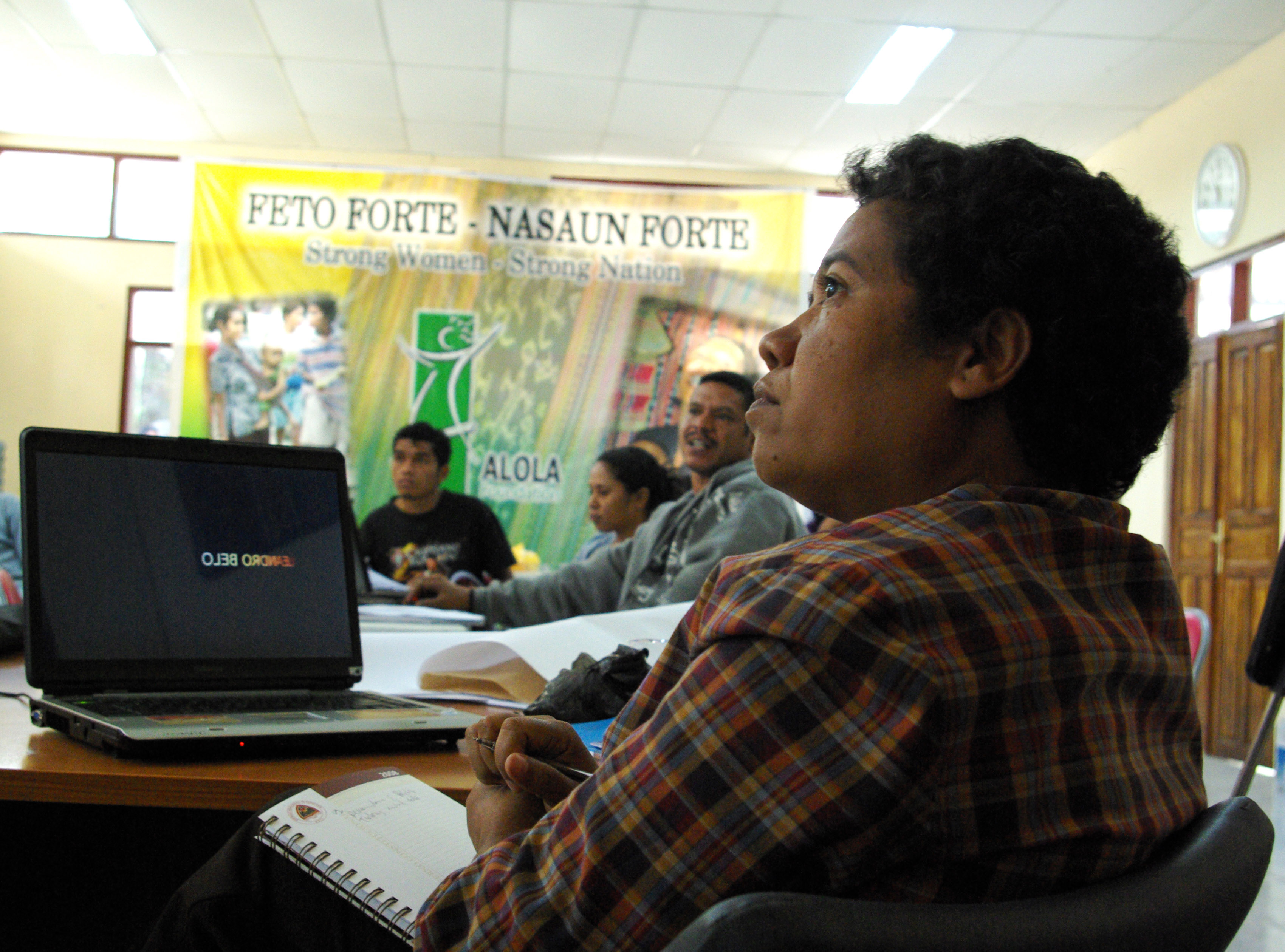 Laura Pina attends a workshop for members of the Women's Caucus, a local Timorese NGO which is preparing the Timor-Leste CEDAW. Behind her a banner reads