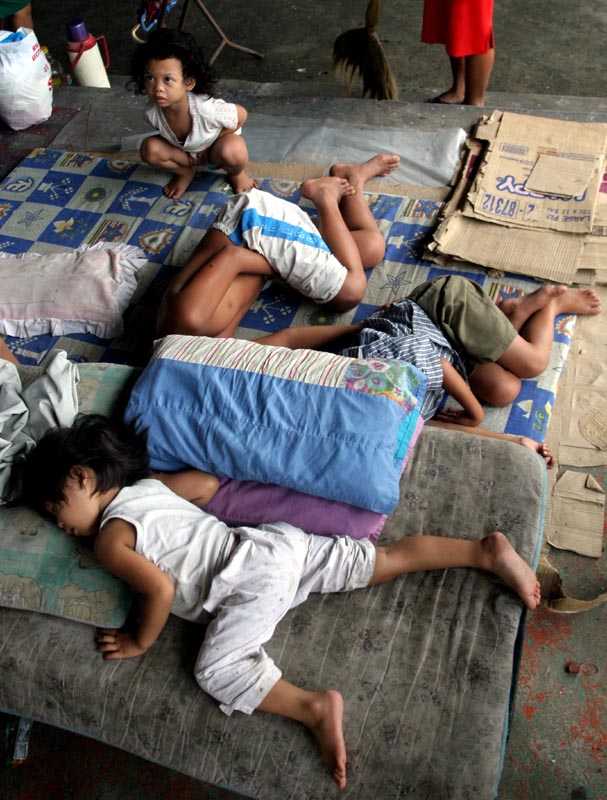Children sleep on the cold concrete floor of an evacuation camp in Manila