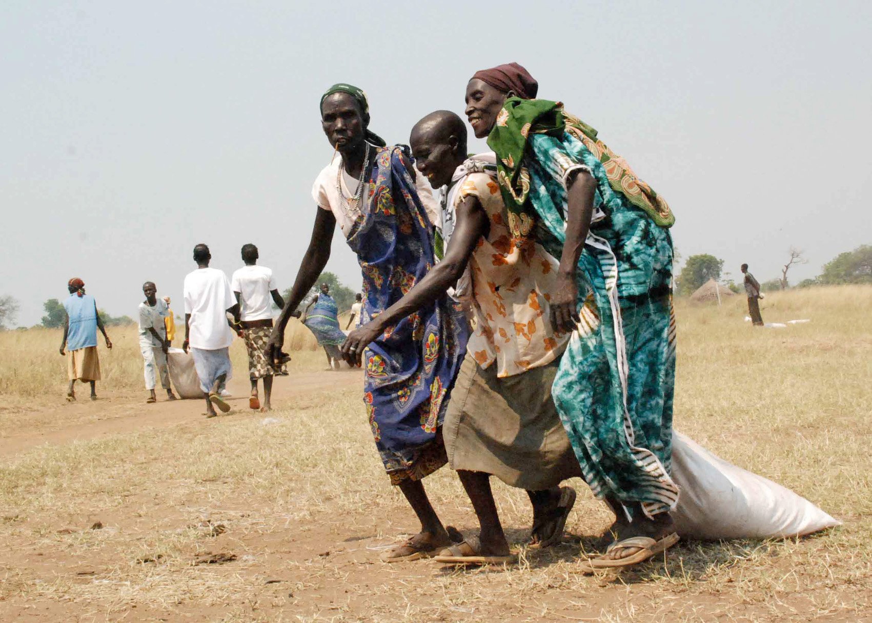 Southern Sudanese women drag bags of grain to a central collection point dropped by WFP chartered airplane in the village of Pochalla, Jonglei state