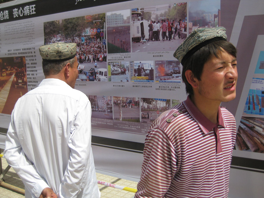 Uyghurs in Xinjiang Province look at posters put up by the Chinese government after the July 2009 protests. The posters show scenes associating Uyghurs with destruction from the protests, or cooperation between Uyghurs and Han Chinese