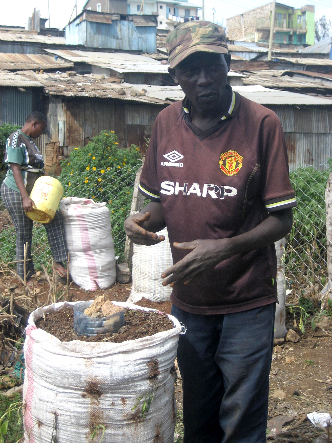 Stephen Ajengo, a member of the Juja Self-Help Group stands by a sack containing vegetable seedlings at an urban farming demonstration plot in Mathare