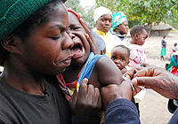 A baby, held by his mother, cries as he receives a vaccine injection at a mobile outreach point in Zimbabwe's Masvingo District during the country's 2009 measles immunization drive