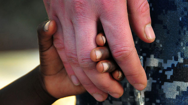 A US Navy Officer holds hands with a Haitian girl during an assessment visit by Sailors assigned to the guided-missile cruiser USS Normandy in response to the earthquake that caused severe damage in Haiti