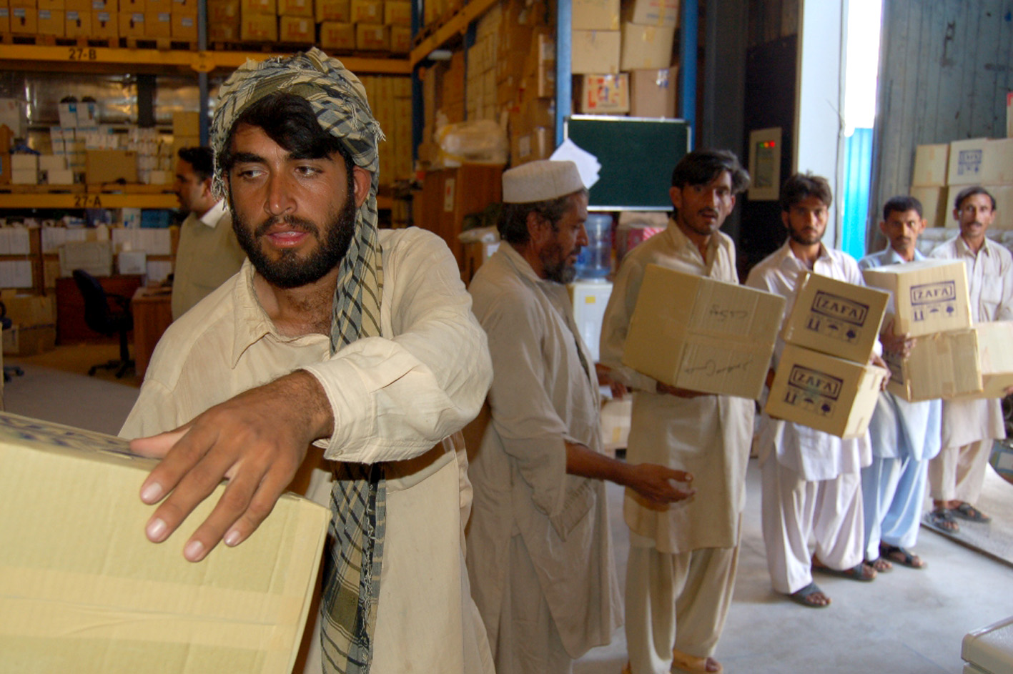 Men load medicine from a WHO warehouse in Islamabad. WHO has delivered medicines and other supplies to treat about two million people