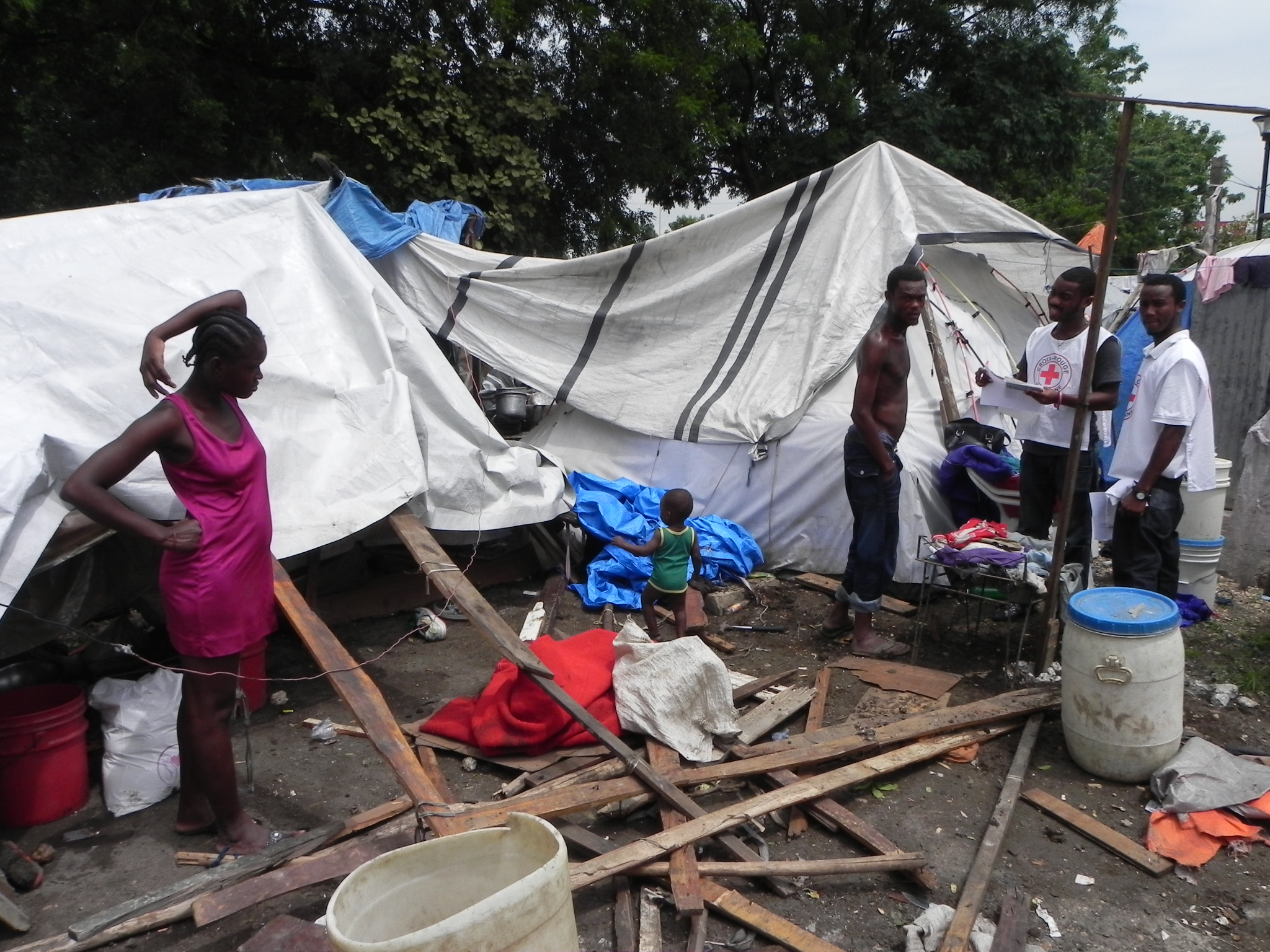 People at Champ de Mars camp for displaced families talk to IFRC emergency response workers about how a 24 Sept 2010 storm wrecked their temporary shelter