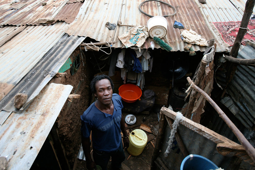 A man stands in front of his dwelling in the Kibera slums
