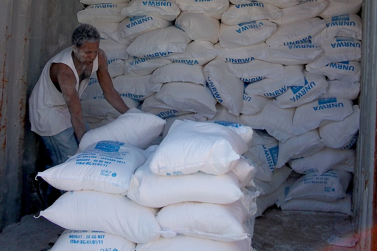 A laborer at a rented UNRWA warehouse transfers flour from containers shipped to Israel’s Ashdod port onto pallets, to be delivered via truck to UNRWA’s 12 distribution centers in Gaza