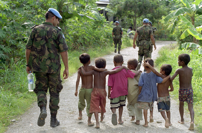 Members of the United Nations Transitional Administration in East Timor (UNTAET) Portuguese contingent are accompanied by a group of local children as they conduct a security patrol in the Becora district of Dili