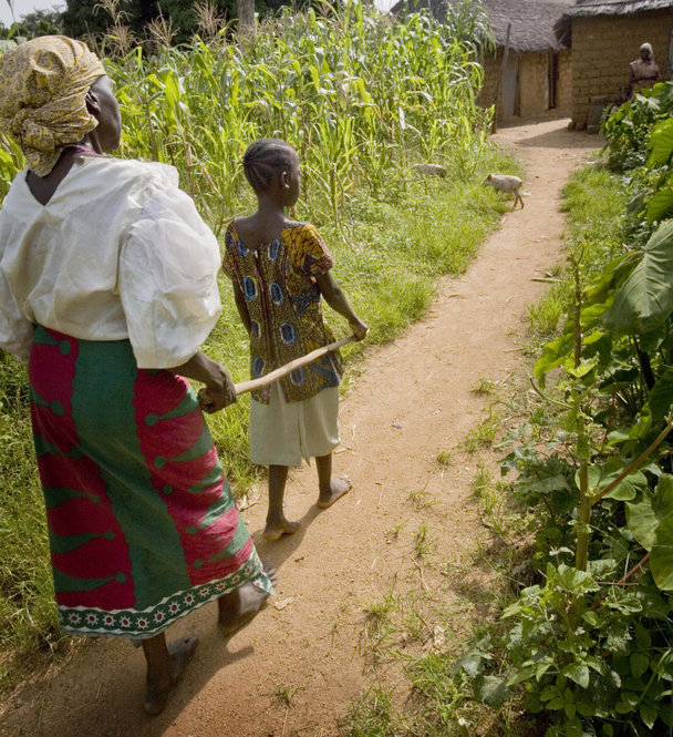 A woman who contracted river blindness many years ago is led along a path by her great granddaughter at her home in Aguna village, Kachia, in Nigeria’s Kaduna State