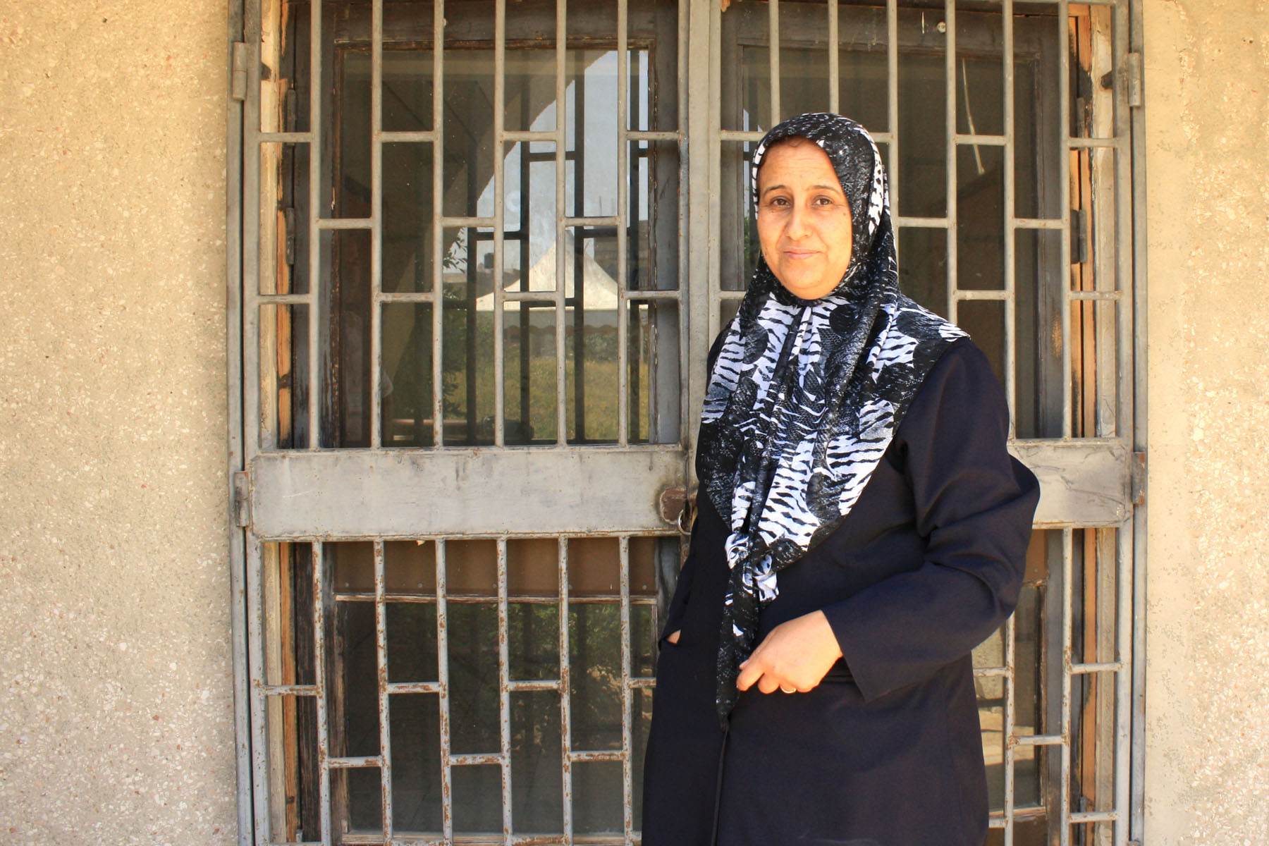 Zainab al Beidi opens a locked gate to the swimming pool that was never completed.