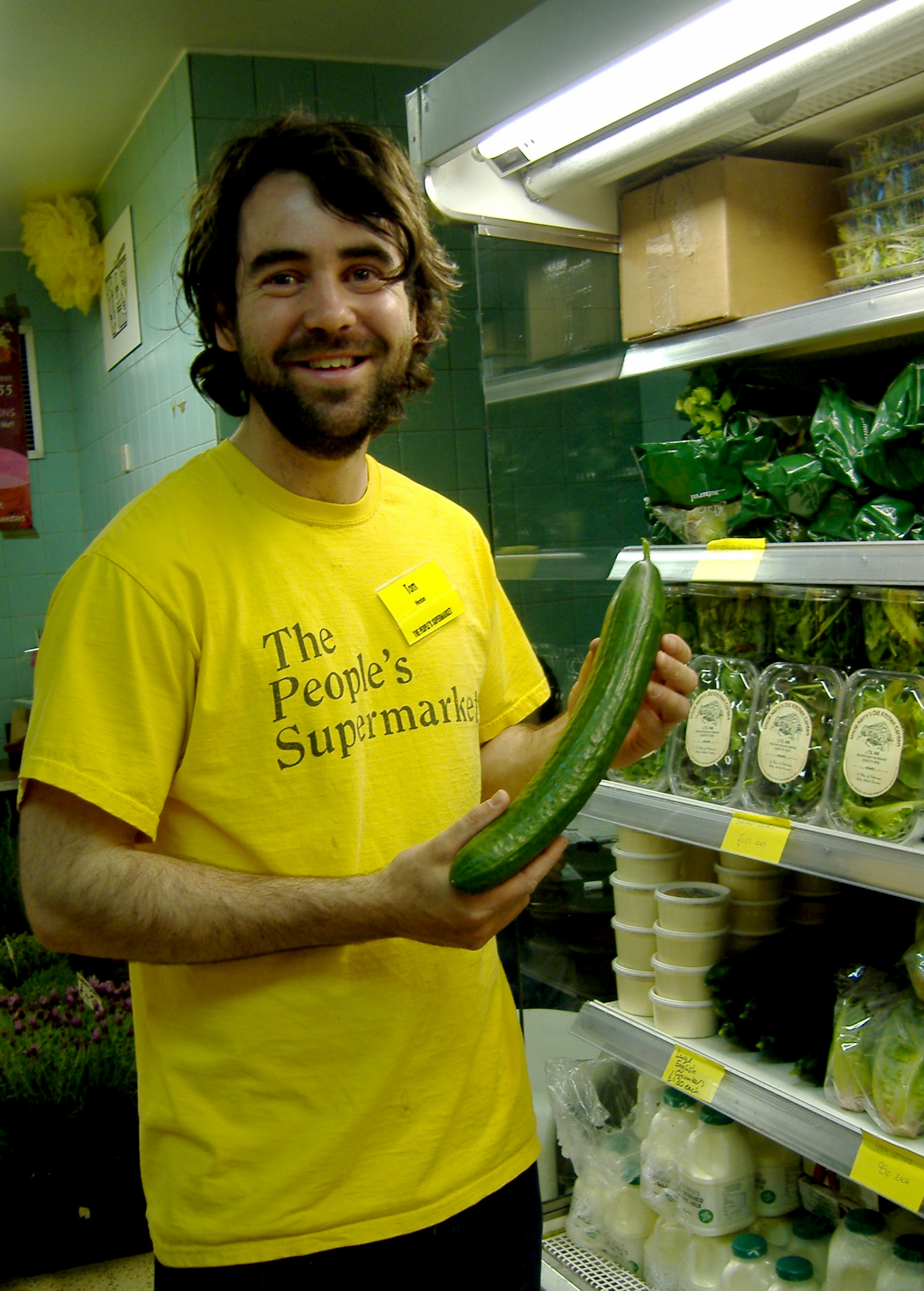 Tom Smith, duty manager at the People's Supermarket, holding a cucumber rejected by a major supermarket on the grounds that it was too big!