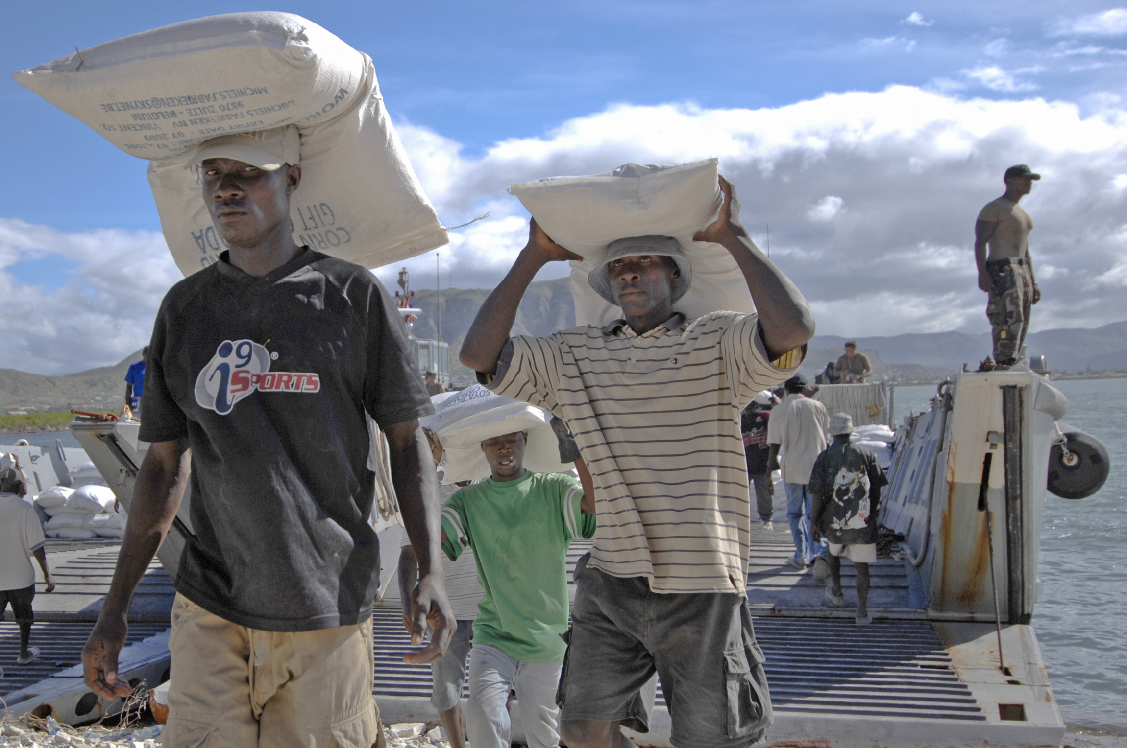 Haitian civilians unload relief supplies from a US Navy ship