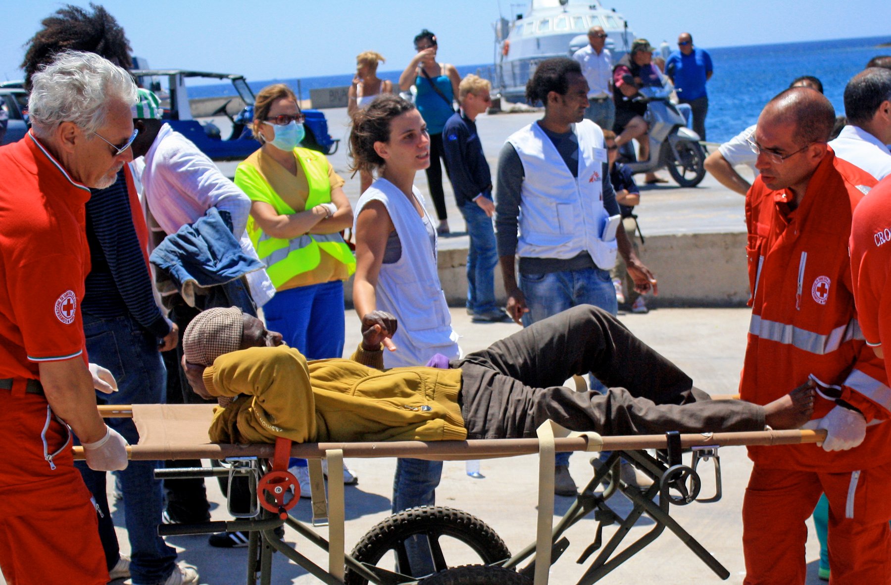 Paramedics from the Italian Red Cross treat an injured migrant worker at Lampedusa's port