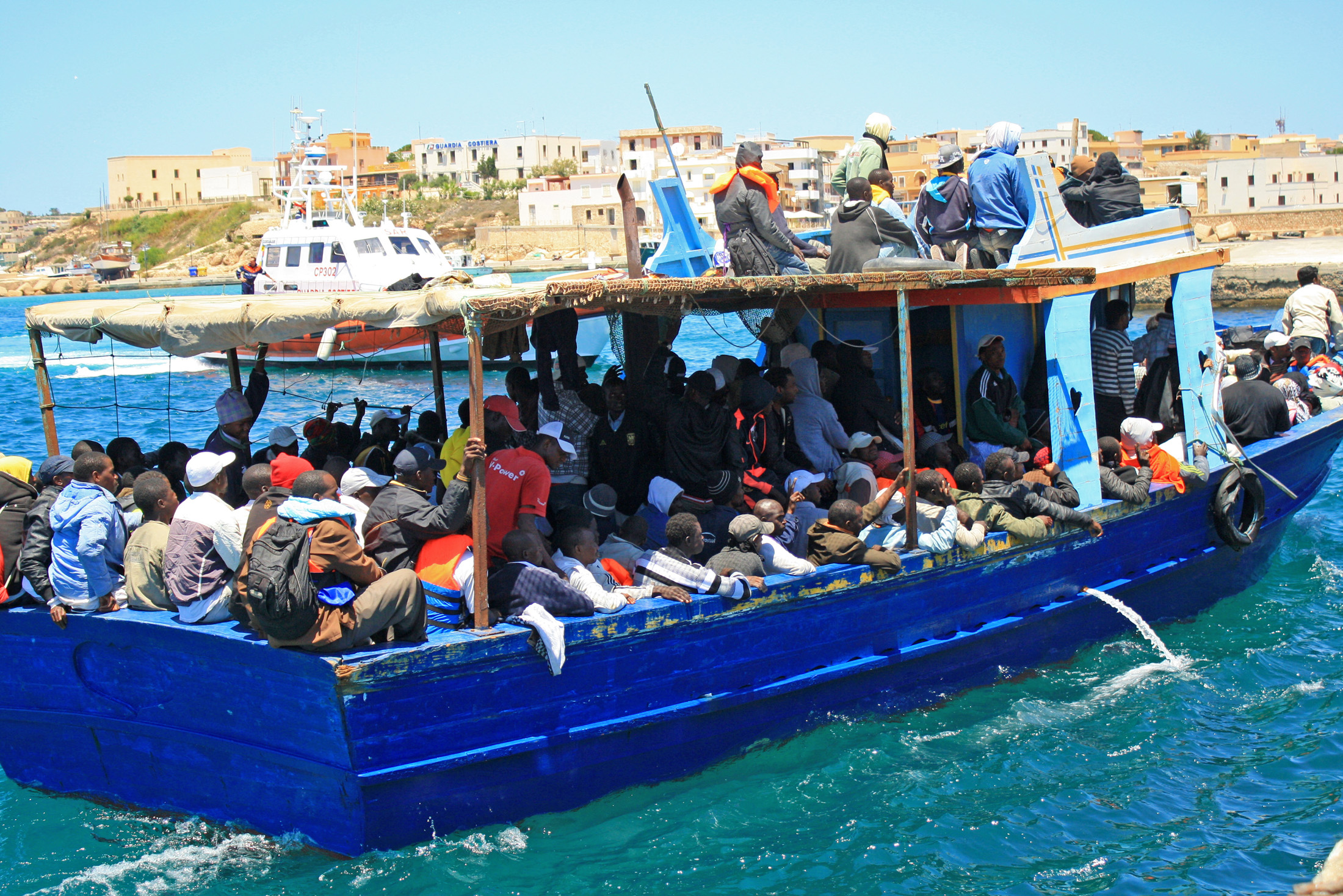 A boat carrying migrant workers and Libyans from Tripoli arrives at the Lampedusa port, escorted by the coastguard
