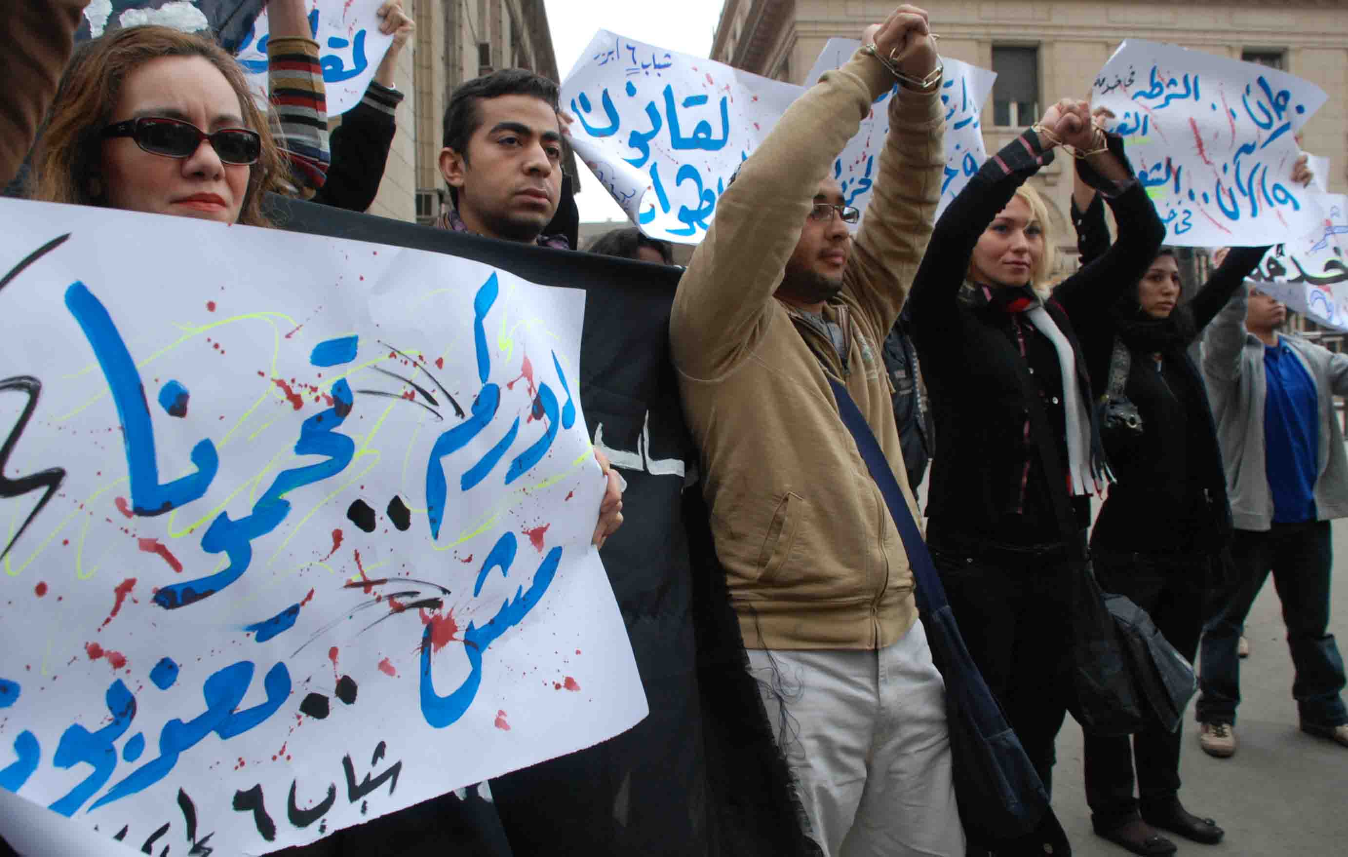 Activists in Cairo protest against police brutality. One of them carries a placard reading: