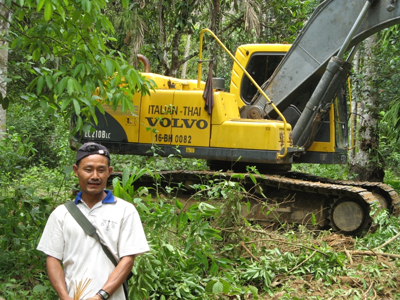 A local resident stands beside road construction equipment outside the southeastern city of Dawei. A major deep water port could displace thousands in the area