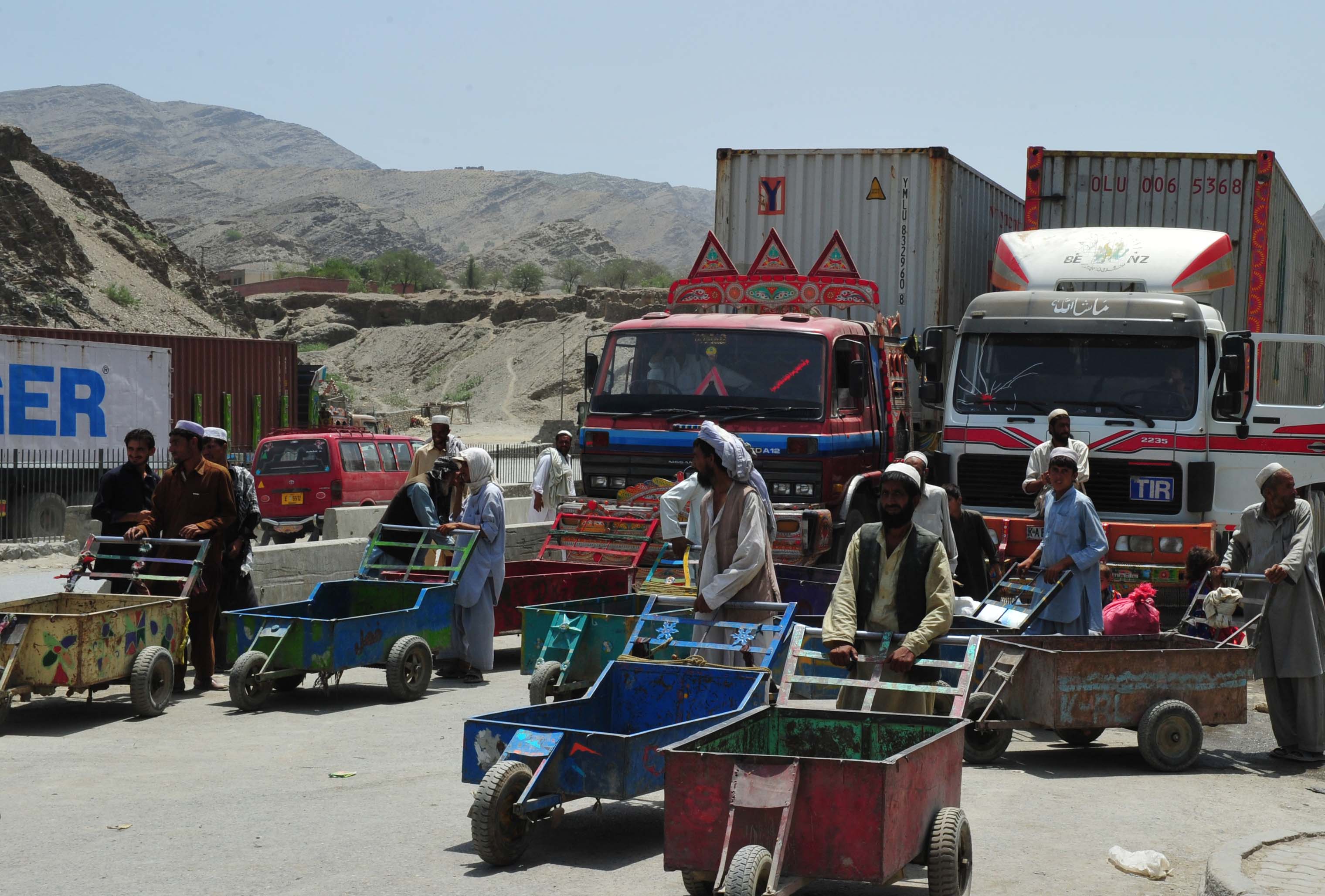 Afghan refugees, living just across the border in Pakistan, search for work at the border by offering to take luggage across.