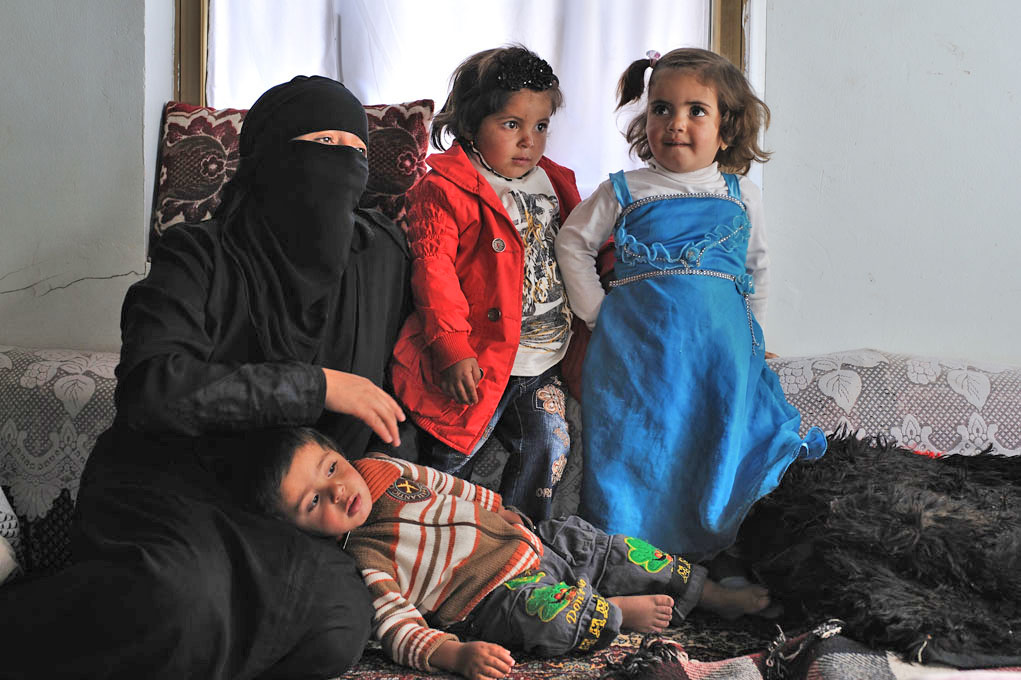 Aisha Haider sits with her daughters and son in a house they are living in temporarily due to damage to their own home. Members of the Murani family, their home was damaged by fighting between tribes from Arhab and the Republican Guard