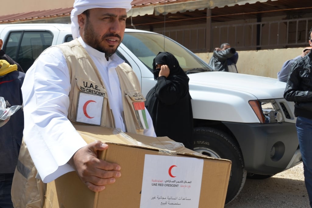 A member of the UAE (United Arab Emirates) Red Crescent distributes aid to Syrian refugees in the northern Jordanian border town of Mafraq. UAE has been active in providing aid in Jordan, but has not done the same inside Syria