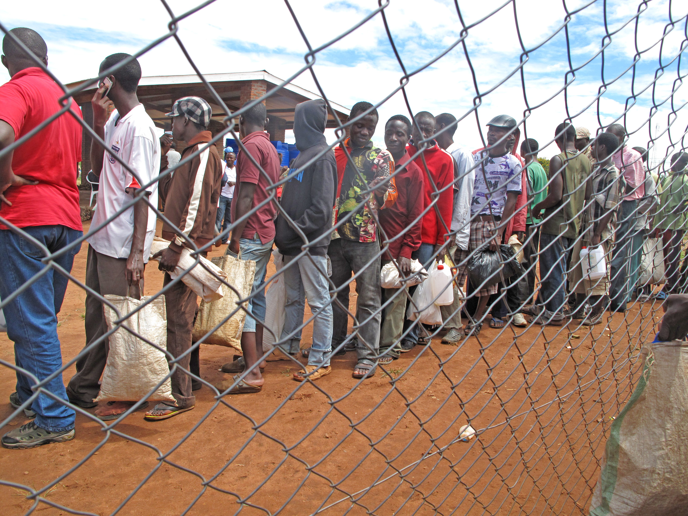 Refugees at Dzaleka camp in Malawi wait in line to collect their monthly food rations which were cut by half in March 2012 due to a funding shortfall