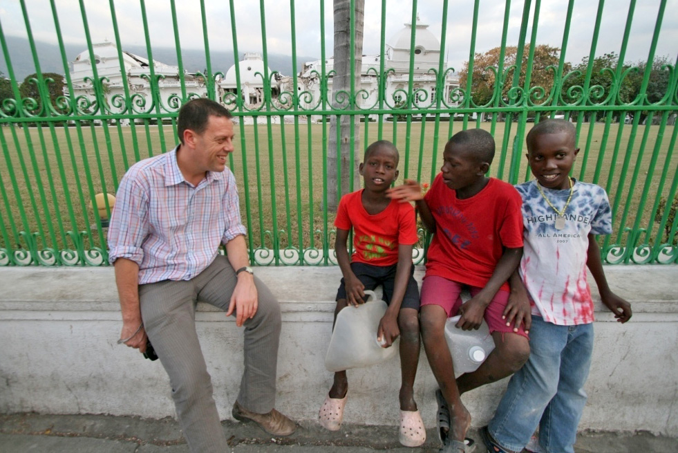 Robert Schofield with some local children in front of the collapsed Haiti presidential palace