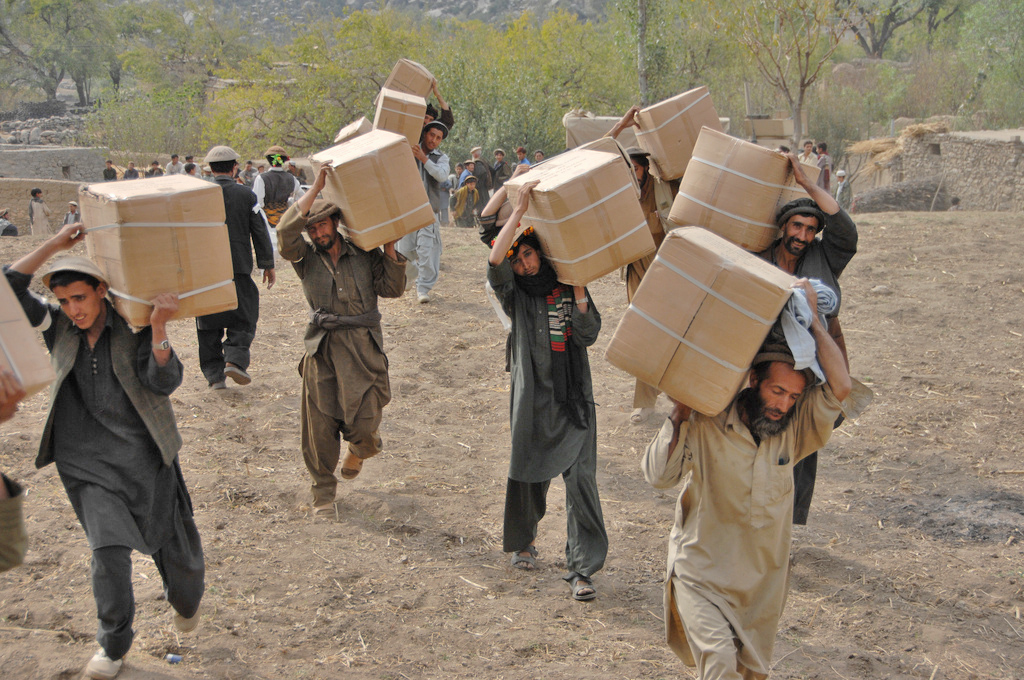 Afghan men from the Wagel valley carry boxes full of humanitarian aid during a handout in the Dudarek village in Afghanistan. The aid included blankets, pots and pans, and women's clothing