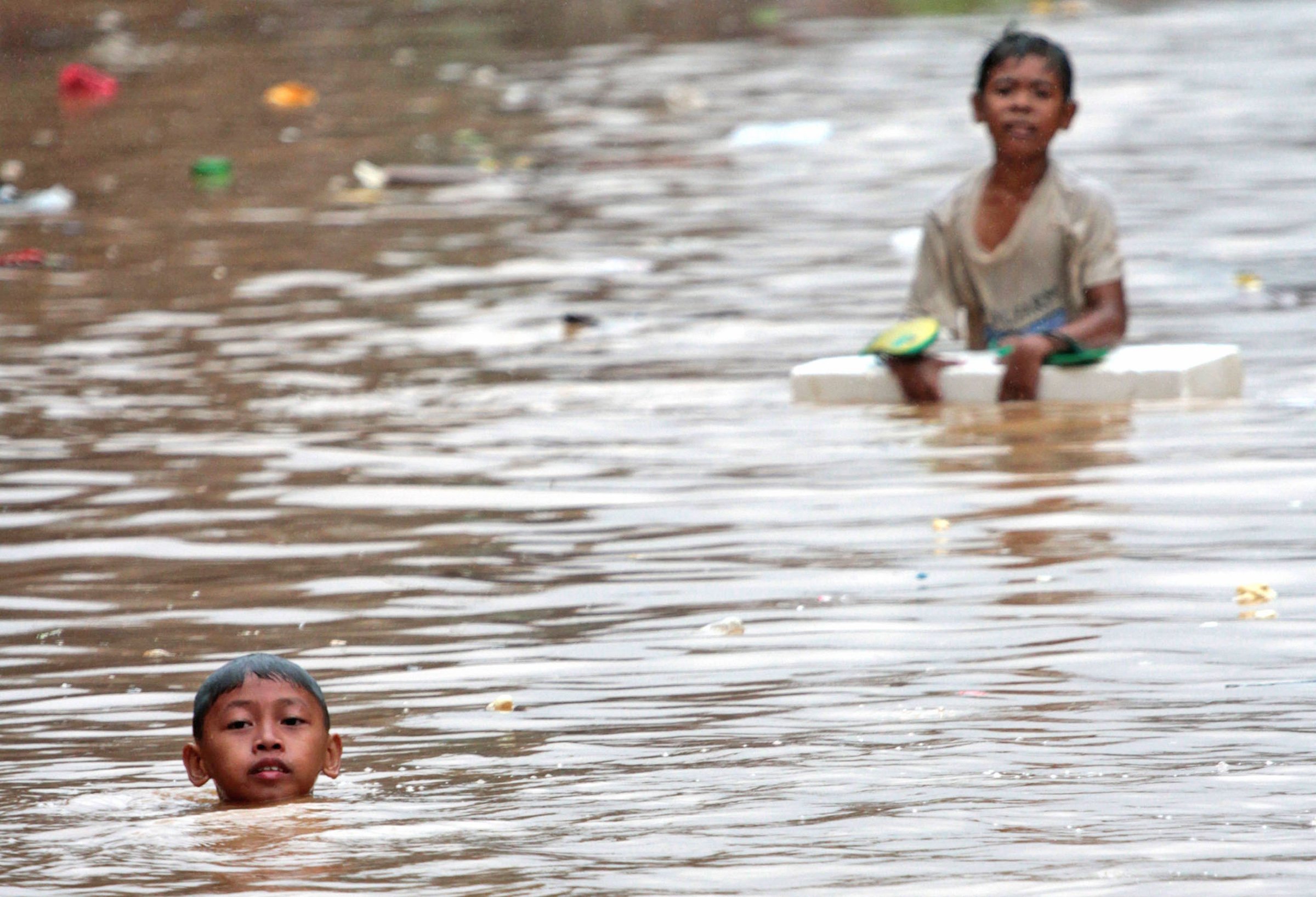 Boys wade in floodwaters in Manila